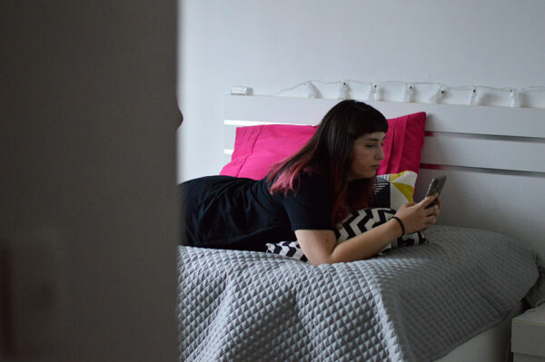 a autora do blog deitada na cama mexendo no celular após terminar o home office do dia